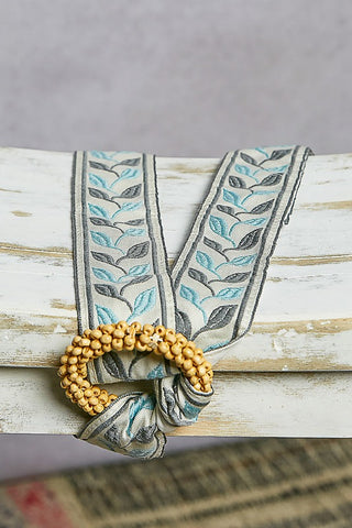 Decorative belt with floral pattern and beaded detail on a textured surface