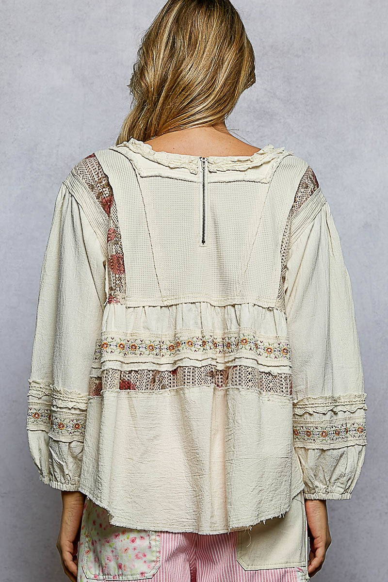 Person wearing a beige jacket with a patterned design on a neutral background