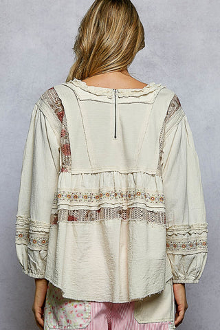 Person wearing a beige jacket with a patterned design on a neutral background