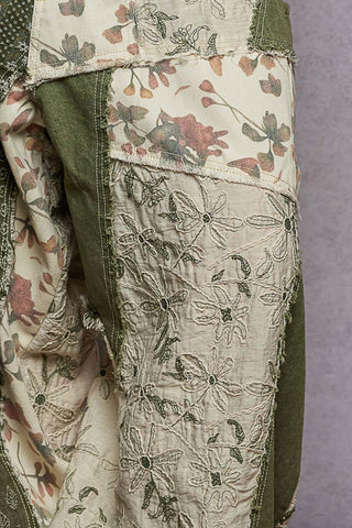 Close-up of a garment with floral embroidery on a plain background