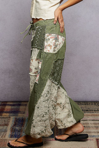 Person wearing a patchwork-style green and floral-patterned skirt with a plain background