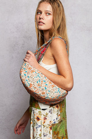 Woman holding a colorful floral-patterned bag against a plain background