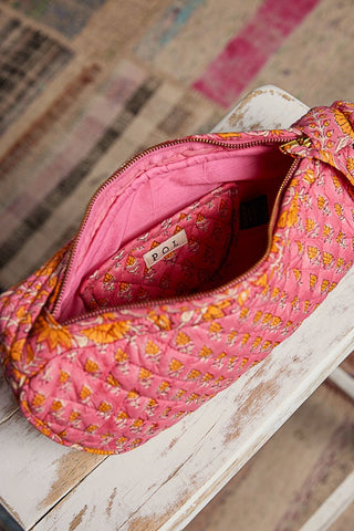 Pink floral-patterned bag with a red interior bag inside, on a wooden surface.