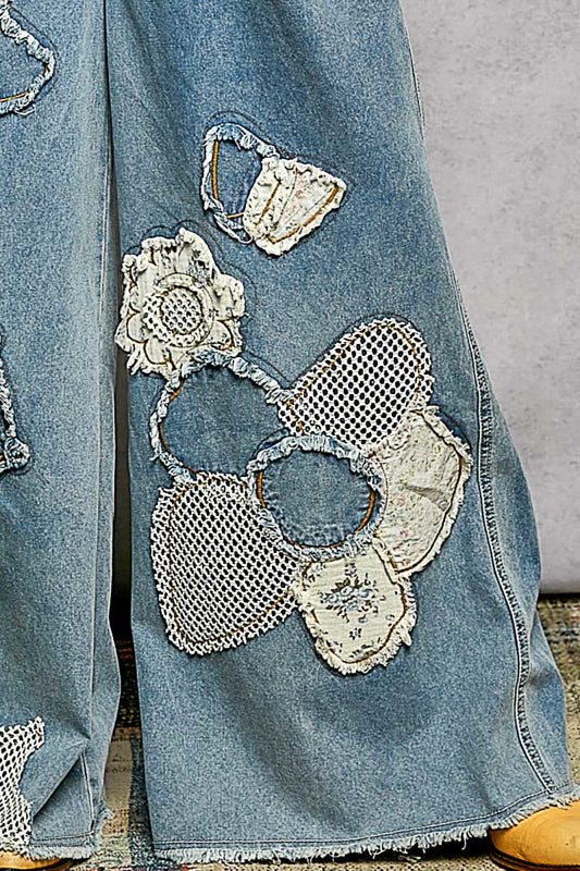 Denim jacket with floral lace patches on a textured surface