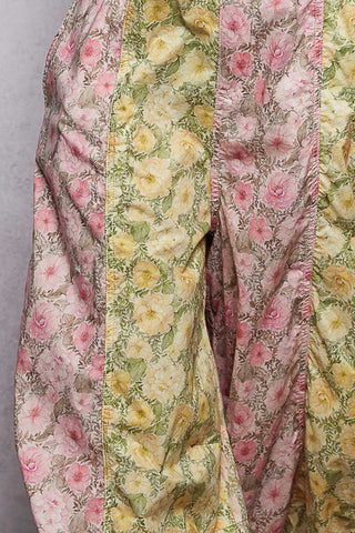 A women wearing floral printed overalls and a white top against a neutral background.
