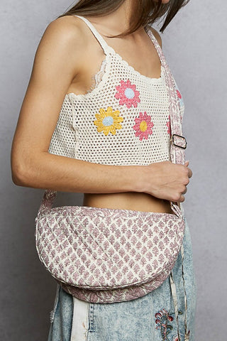Person wearing a crochet top with floral patterns and a matching bag on a gray background