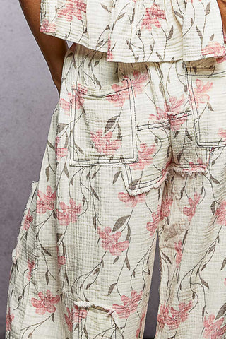 Floral patterned outfit with a focus on pants against a neutral background
