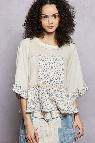 Woman wearing a floral blouse with ruffled sleeves against a gray background