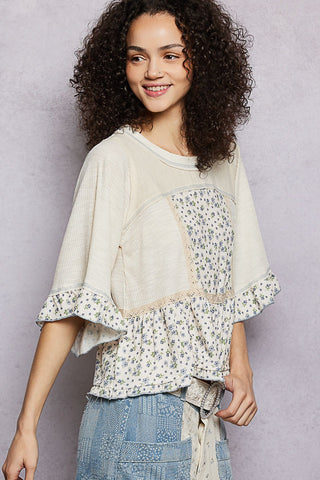 Woman wearing a layered outfit with a floral top and denim skirt against a plain background
