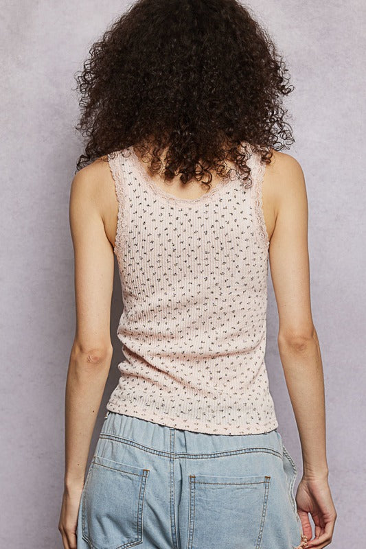Person wearing a sleeveless top with a subtle pattern and light blue jeans against a plain background