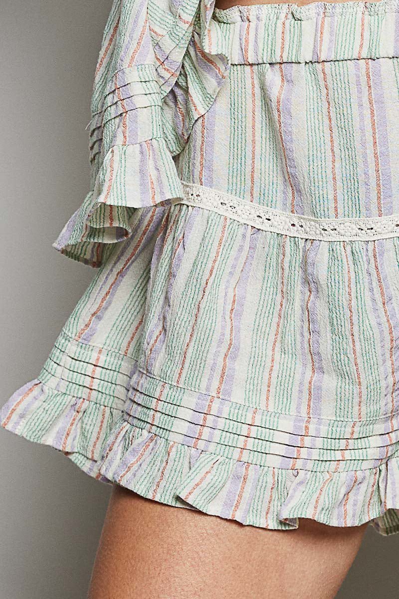 Green and multicolor striped skirt with ruffled layers on a neutral background