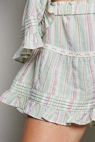 Green and multicolor striped skirt with ruffled layers on a neutral background