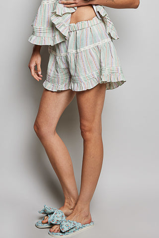 Person wearing a striped outfit with ruffled shorts on a plain background