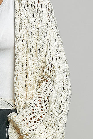 A Women wearing a colour knit cardigan on a neutral background.