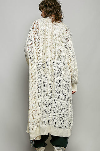 A Women wearing a colour knit cardigan on a neutral background.