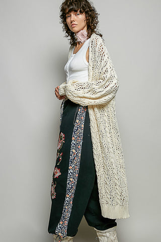 A Women wearing a colour knit cardigan on a neutral background.