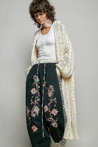 A Women wearing a colour knit cardigan on a neutral background.