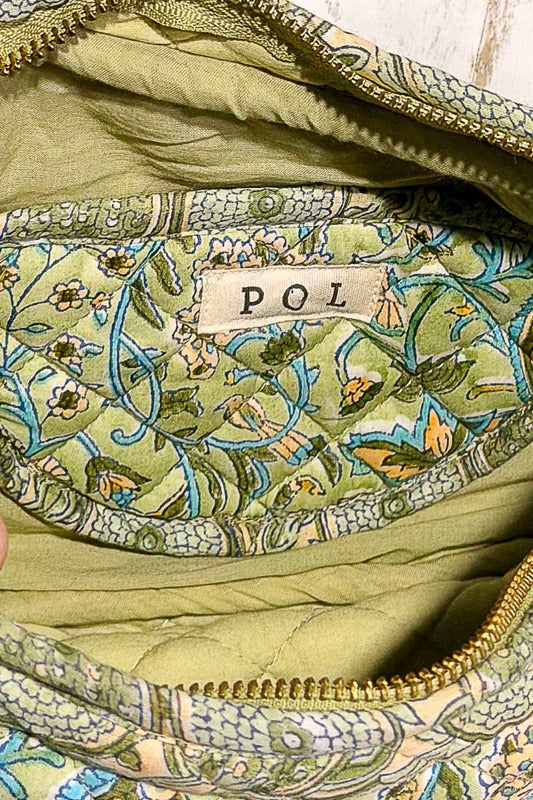 Close-up of a green fabric with floral patterns and a 'POL' label.