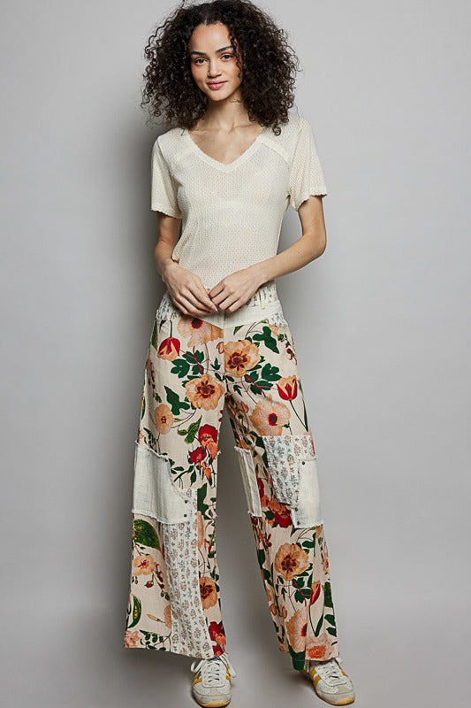 Woman wearing a white top and floral pants on a gray background