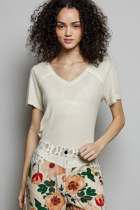 Woman wearing a light-colored knit top and floral skirt against a plain background