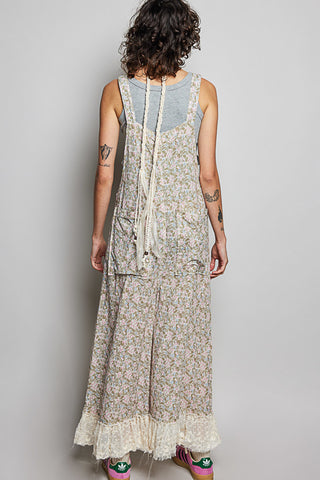 Person wearing a long floral dress over a denim top against a plain background