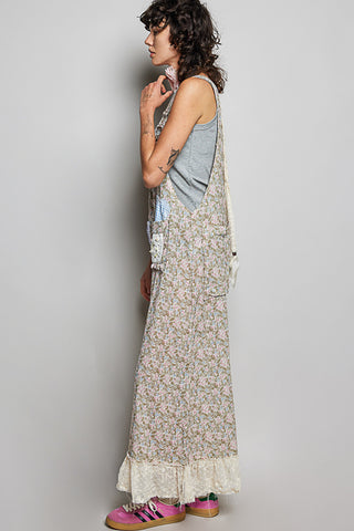 Woman wearing a long floral dress over a tank top against a plain background