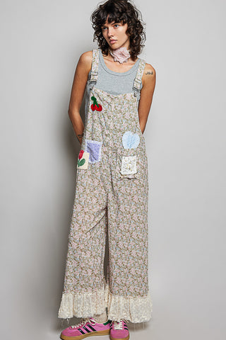 Woman wearing a floral overalls with patches on a plain background