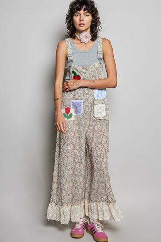 Person wearing floral overalls with patchwork design on a plain background