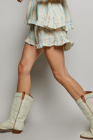 Person wearing a plaid skirt and white boots with brown soles on a plain background