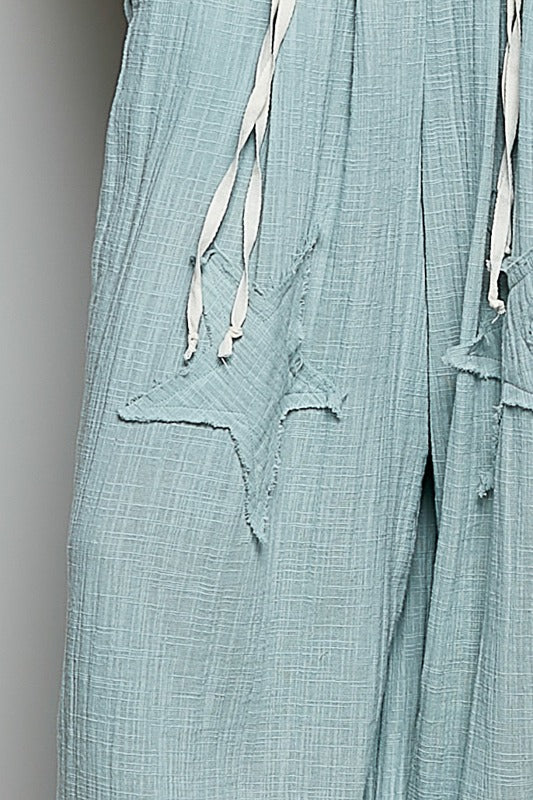 Light blue pants with lace detailing on a gray background