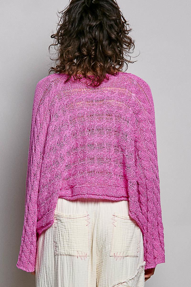Person wearing a pink knitted sweater and white pants on a plain background