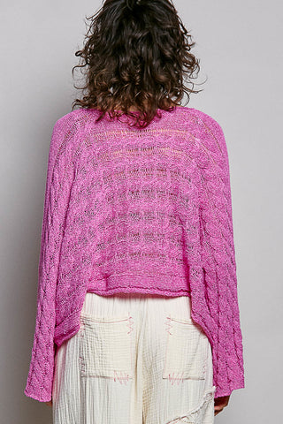 Person wearing a pink knitted sweater and white pants on a plain background