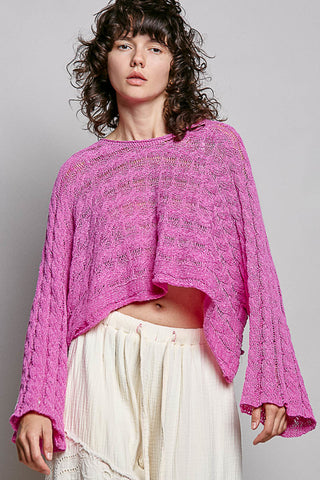 women wearing a bright pink knit sweater on a grey background