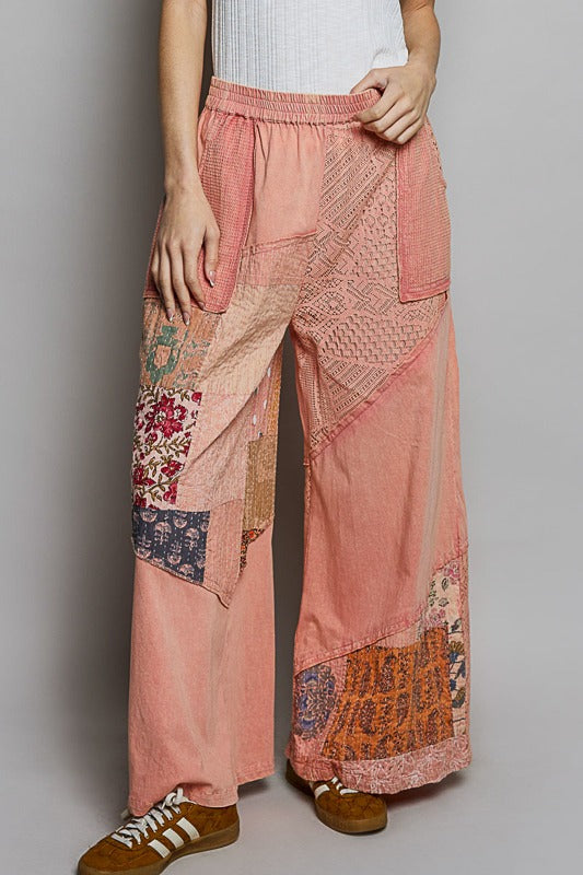 Person wearing pink patchwork pants on a plain background