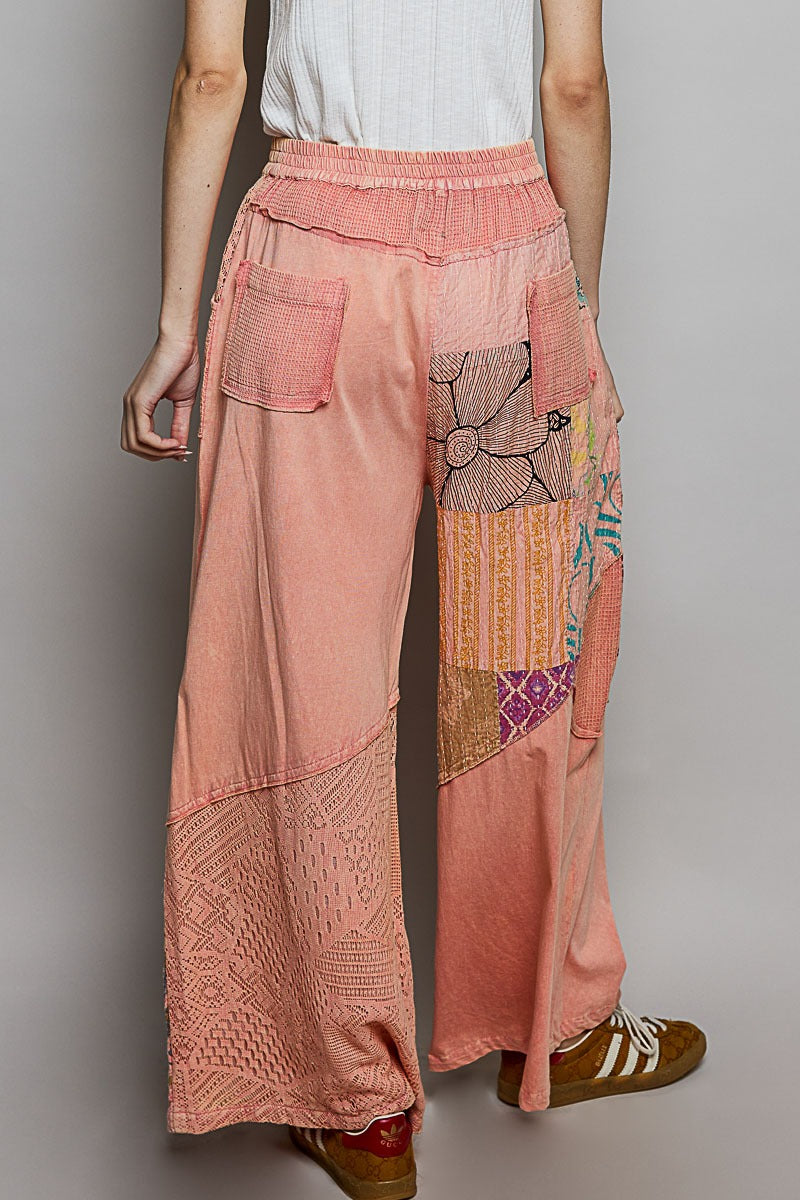 Person wearing a pair of pink patchwork pants on a plain background