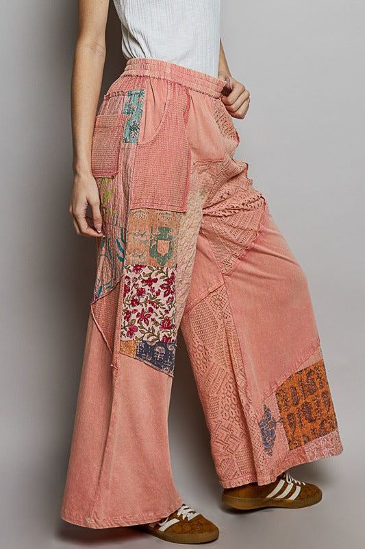 Person wearing pink patchwork pants on a plain background