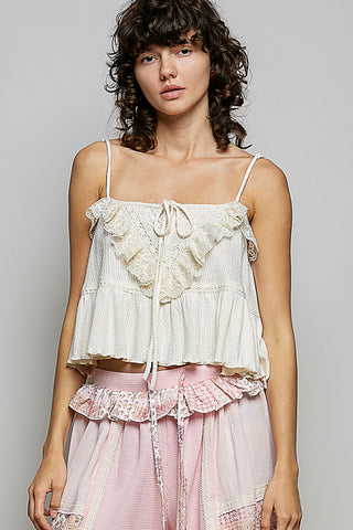 Woman wearing a white lace top and pink skirt against a gray background