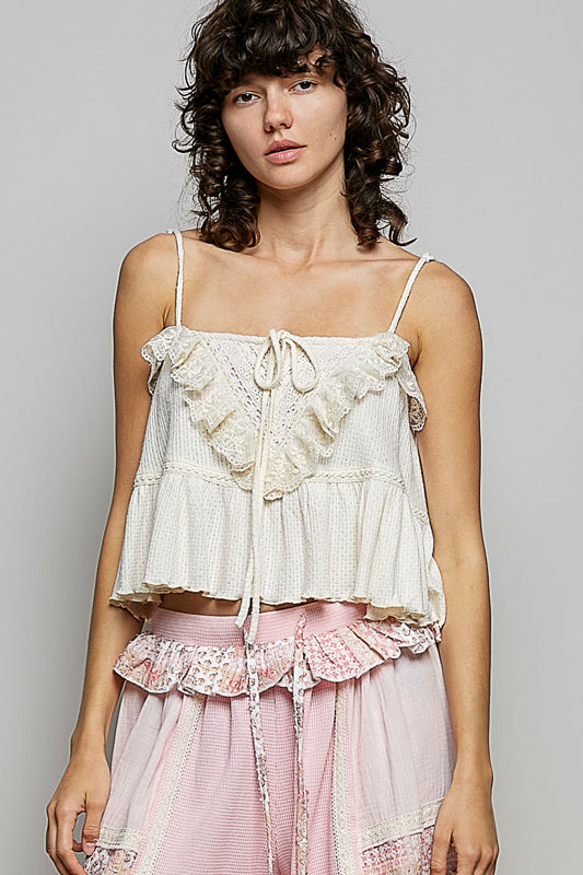 Woman wearing a white lace top and pink skirt against a gray background