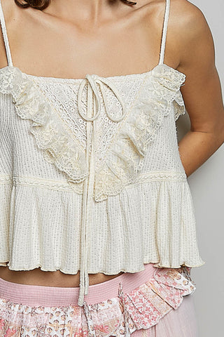 Light-colored lace top with ruffled details on a neutral background