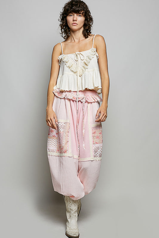 Woman wearing a white top and pink pants against a gray background