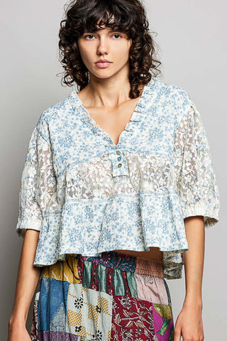 Woman wearing a floral blouse with a colorful skirt against a gray background