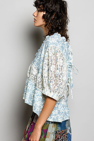 Woman wearing a light blue floral blouse with a blurred background