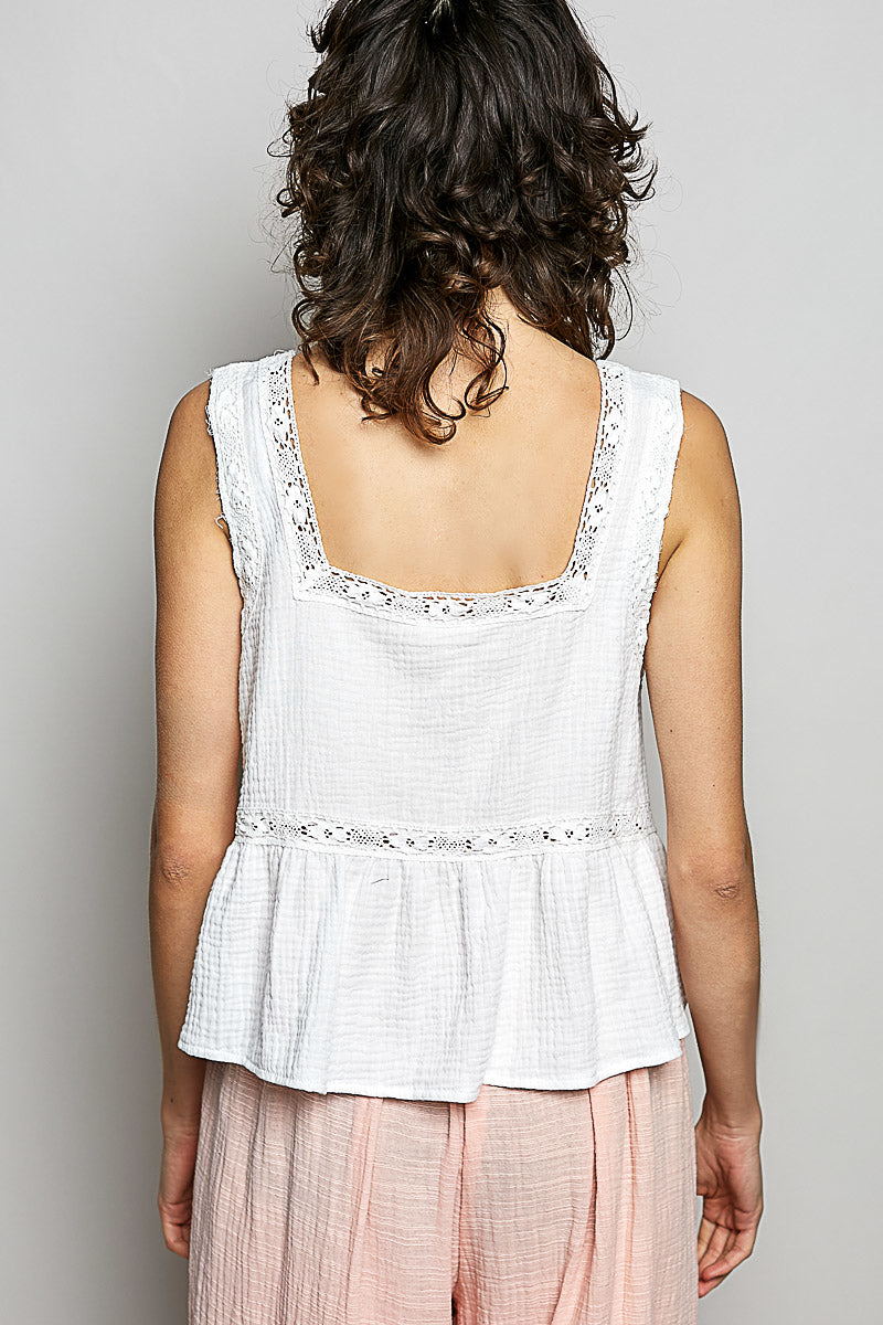 A women wearing a white tank top with a floral patch on it.