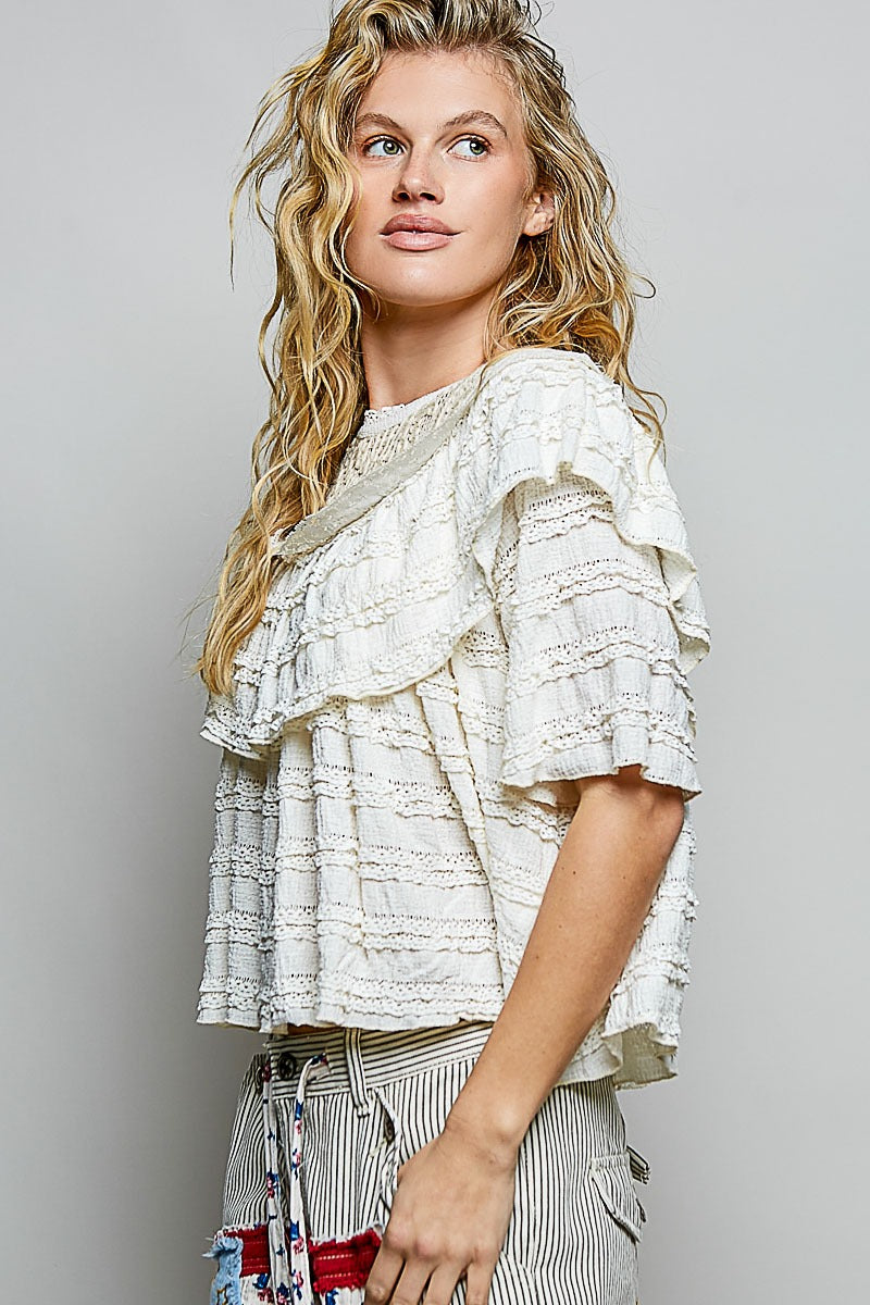 Woman wearing a white ruffled top with a gray background