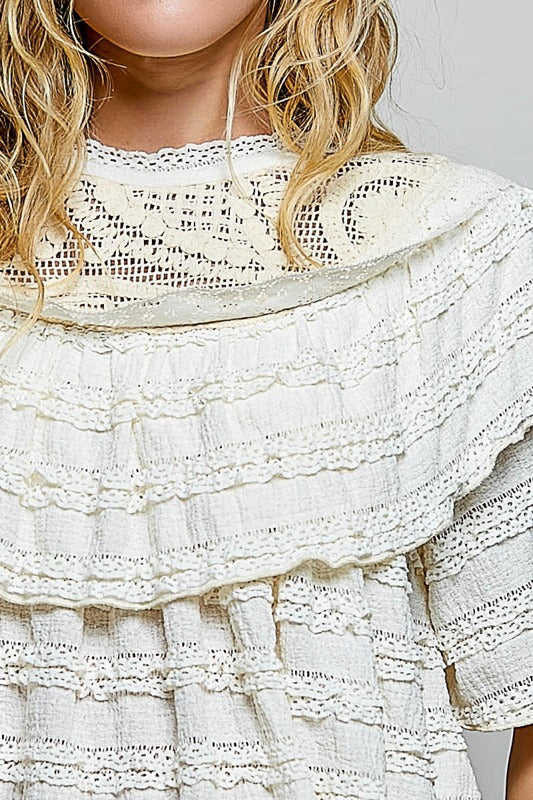Close-up of a white lace dress with ruffled layers.