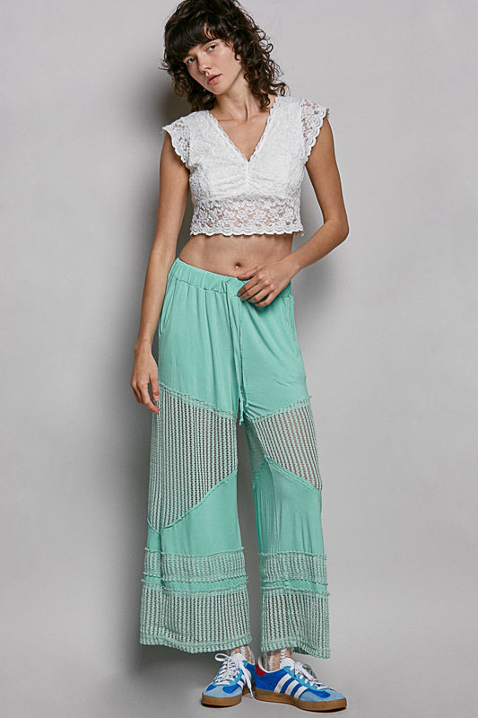Women wearing a white lace crop top on a plain background. 