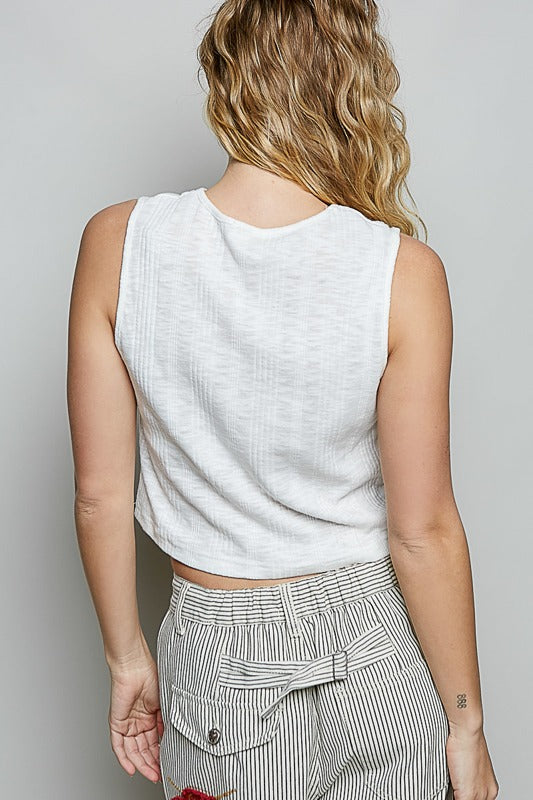 Person wearing a white sleeveless top and striped pants on a plain background