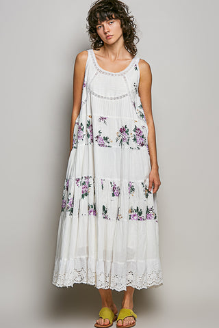 Woman wearing a white floral dress against a plain background