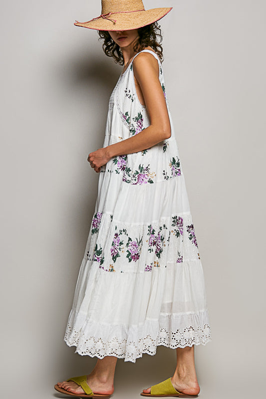 Woman wearing a white floral dress with a straw hat on a plain background