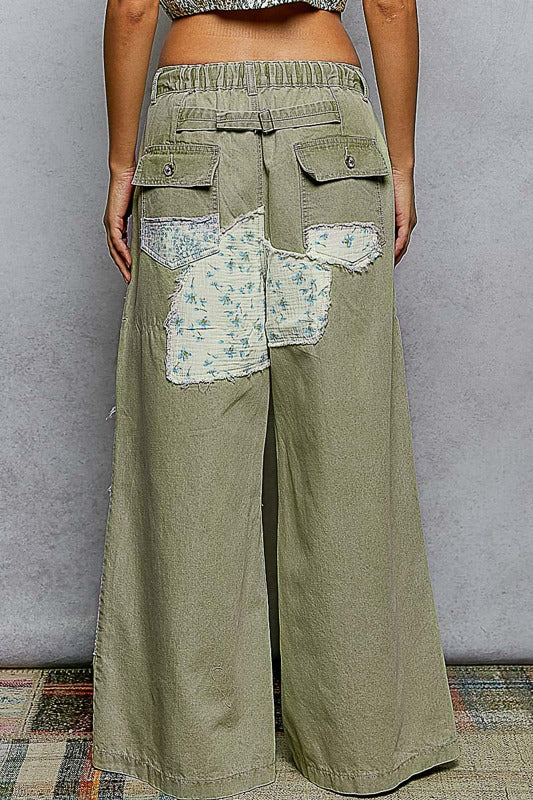 Green patchwork pants worn by a person against a plain background